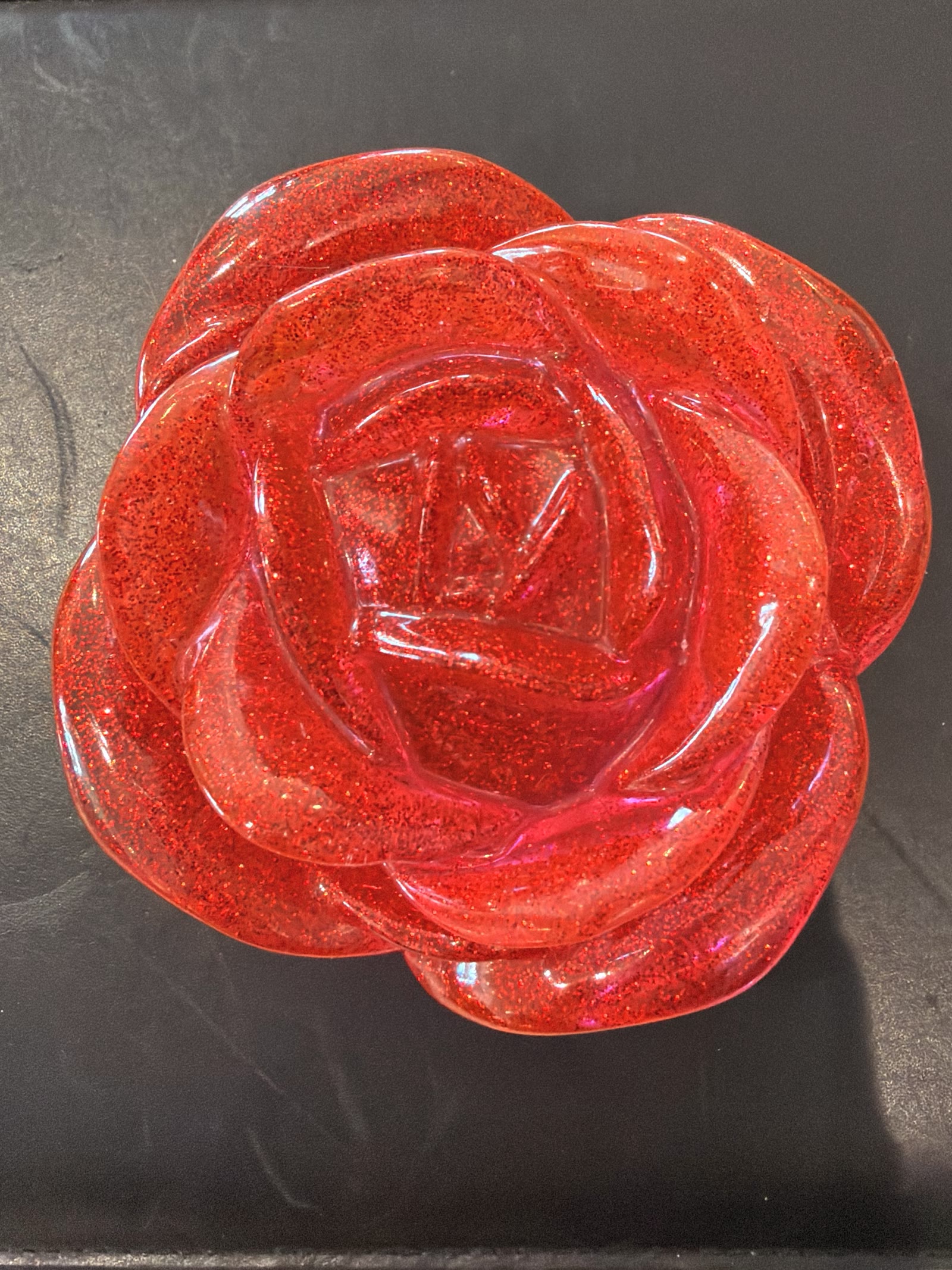 Three-dimensional translucent red resin rose packed with fine red glitter, photographed from above